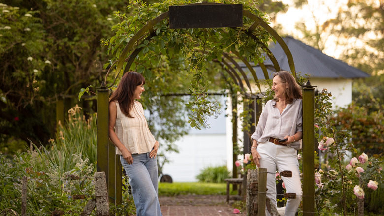 Women standing next to a garden arbor