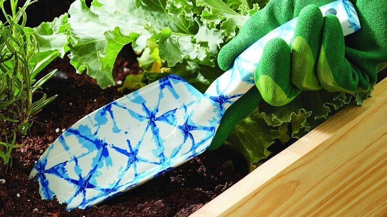 A hand with a green glove using a trowel from the Gardener Shibori Garden Tool Set from Walmart.