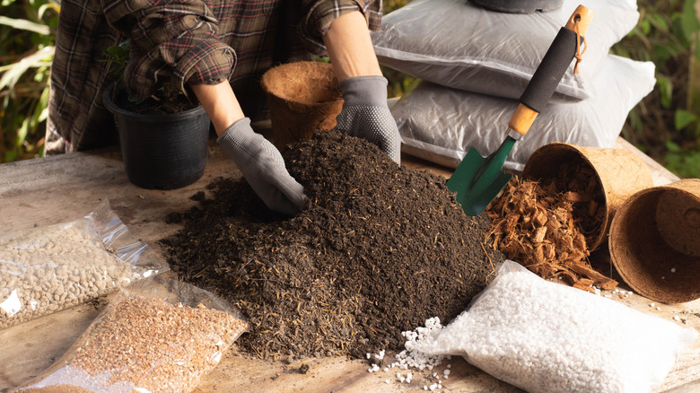 person with gloves on mixing potting soil with gravel and mulch
