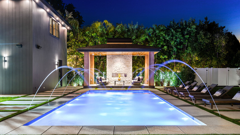 Luxurious modern backyard lit up with lights