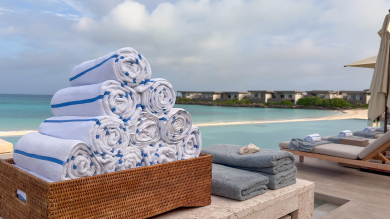 Pile of beach towels with blue dobby weave stripe on a table near the beach