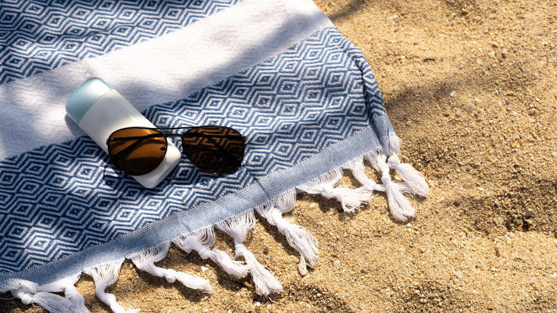 Sunglasses and sunscreen on a beach towel