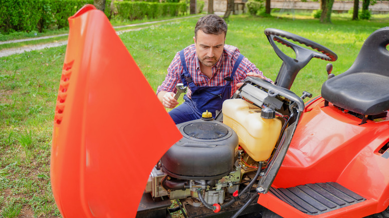 Man inspecting engine on riding lawnmower