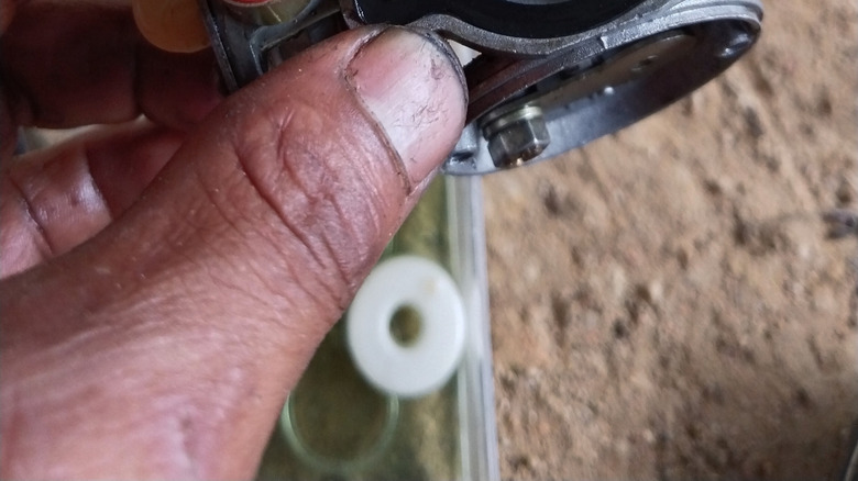 Hand holding a lawn mower carburetor