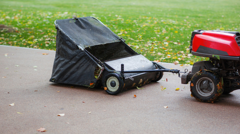 A lawn sweeper attachment on the back of a riding mower