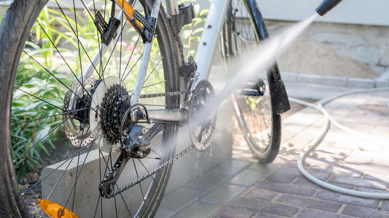 A pressure washer nozzle spraying water on a bicycle wheel.