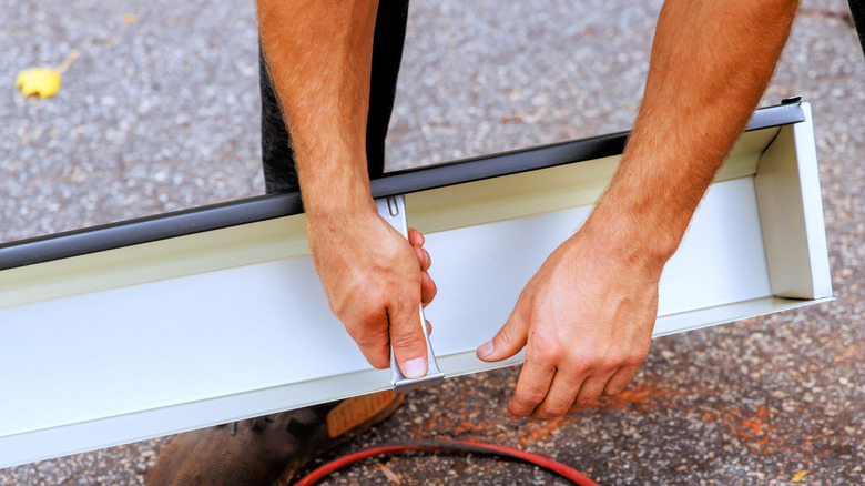 hands holding onto rain gutters
