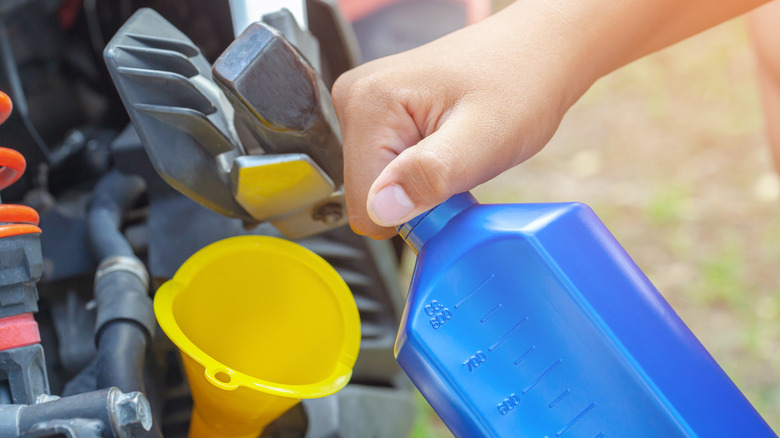 bottle of oil next to funnel in lawn mower