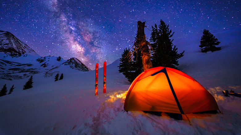 Camping tent in the snow set against starry sky