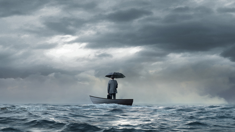 Man boat holding umbrella cloudy ocean