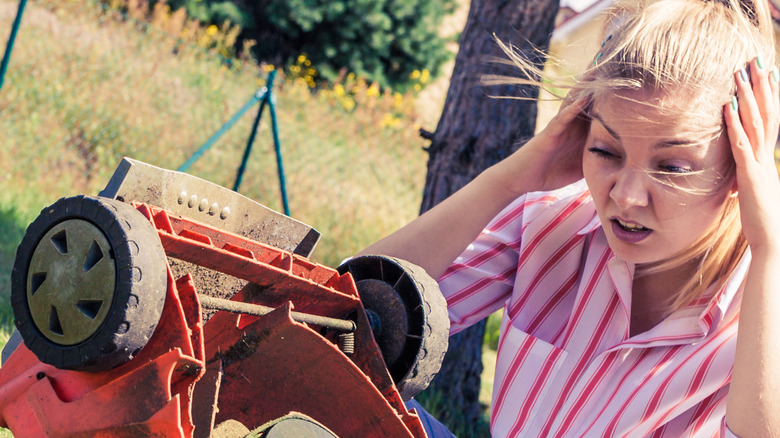 Woman seeing gas leak on old lawn mower