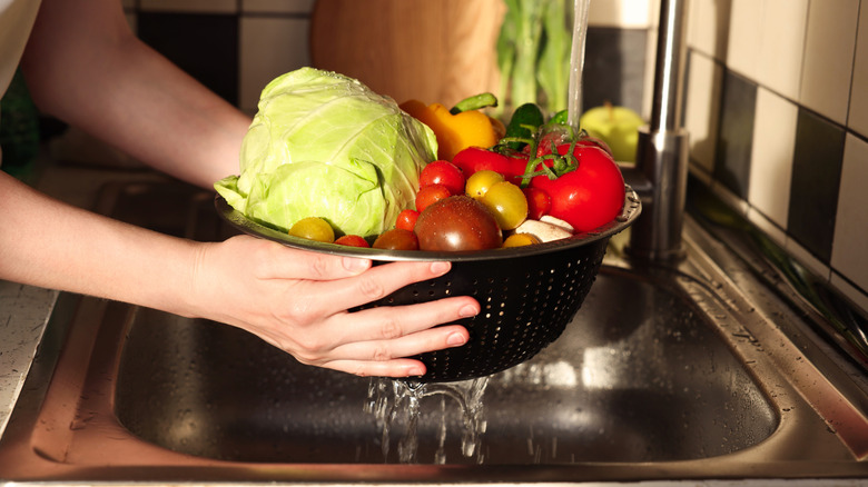 washing bowl of vegetables in sink