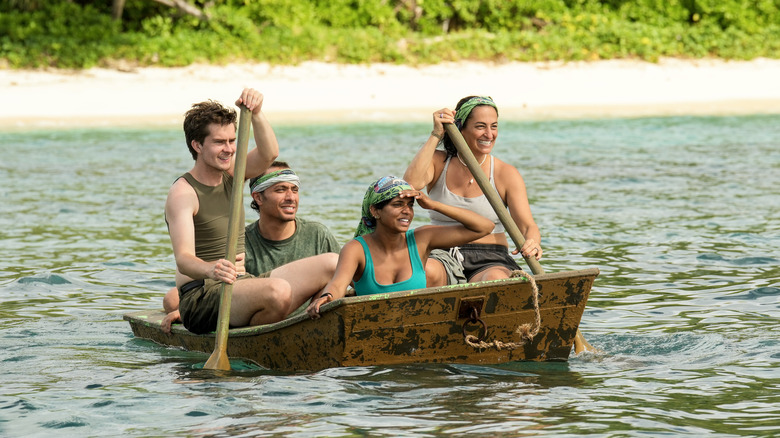 Survivor contestants paddling in a boat