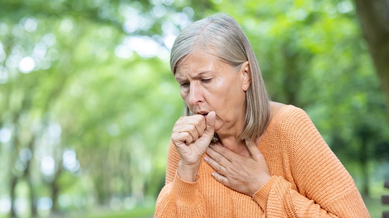 Elderly woman coughing in discomfort