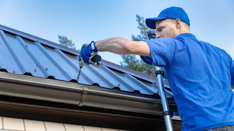 Person on a ladder, installing a metal roof