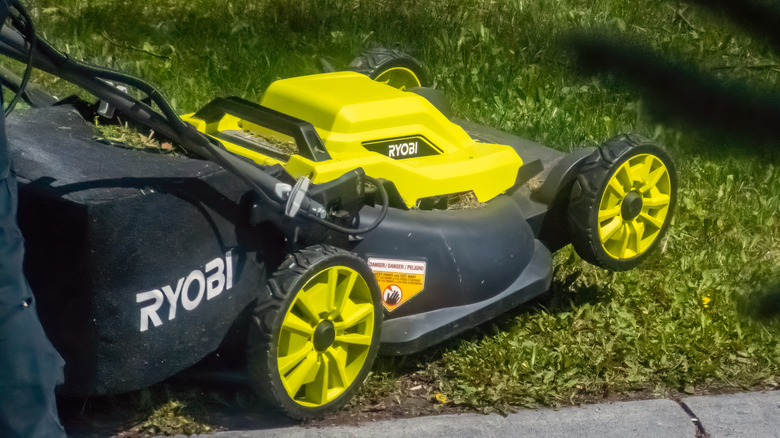 Person using a Ryobi lawnmower to cut their grass