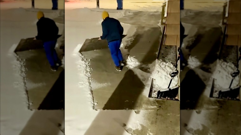 Man clears snow with plywood