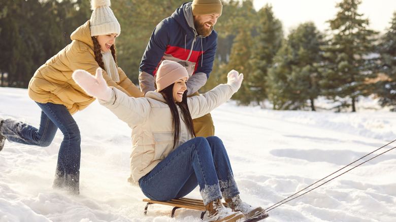 Three people snow sledding