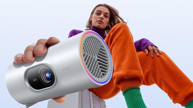 A woman in colorful clothes holding the JMGO PicoPlay towards the camera below her