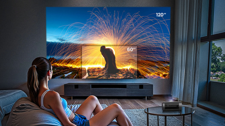 A woman on a beanbag in a room, looking at an example of how large the JMGO projector screen can be
